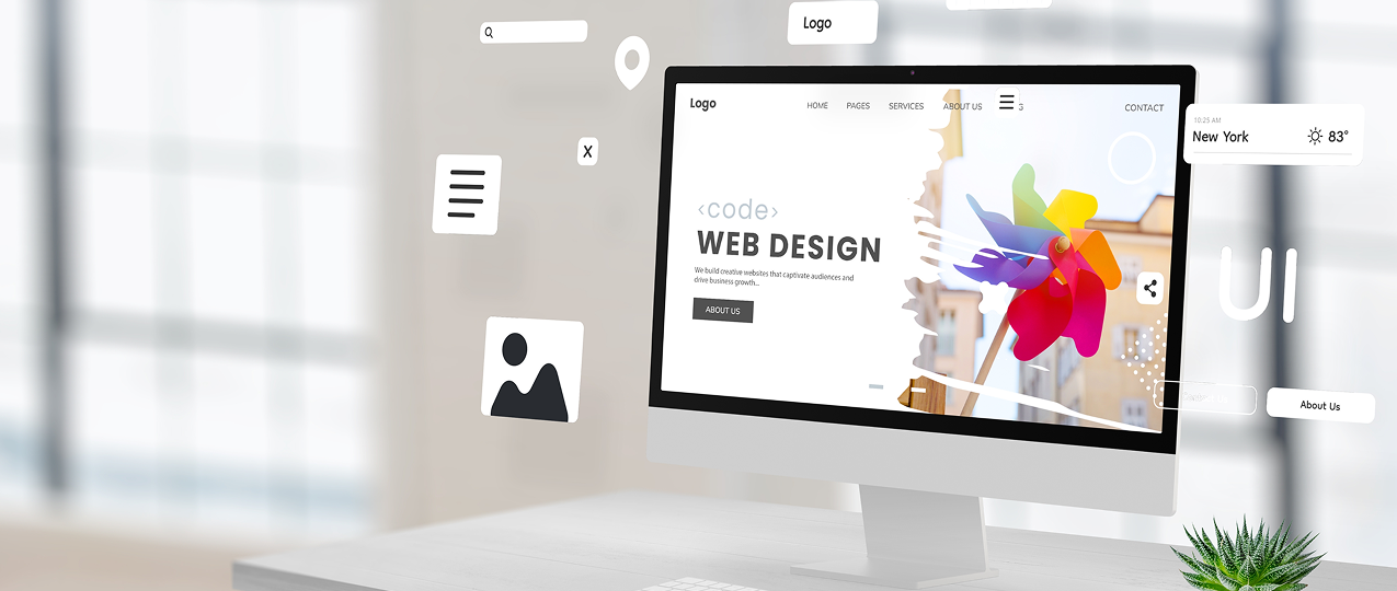 Desktop computer displaying a colorful web design homepage with floating graphic elements.