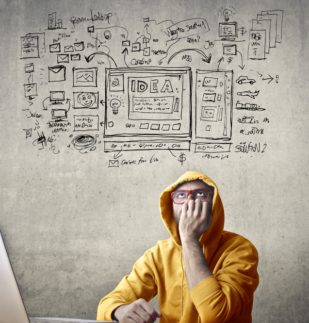 A person in a yellow hoodie looks contemplative in front of a wall with design sketches.